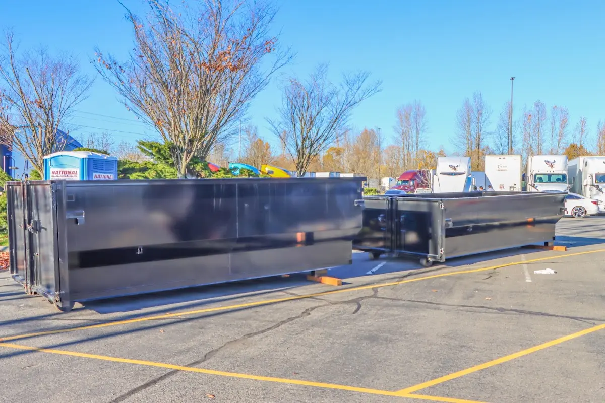 Professional dumpster rental service with roll-off container on residential driveway in West Pensacola